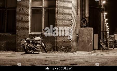 Une moto la nuit, une moto se tient sous une lumière de rue, un croiseur, une moto d'époque, une photo en noir et blanc Banque D'Images