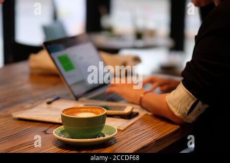 une femme utilisant un ordinateur portable, travaillant dans un café. Arrière-plan flou Banque D'Images