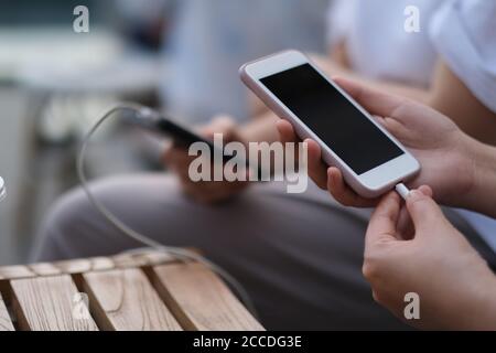 gros plan sur des personnes partageant une batterie portable pour recharger leur téléphone. arrière-plan flou Banque D'Images