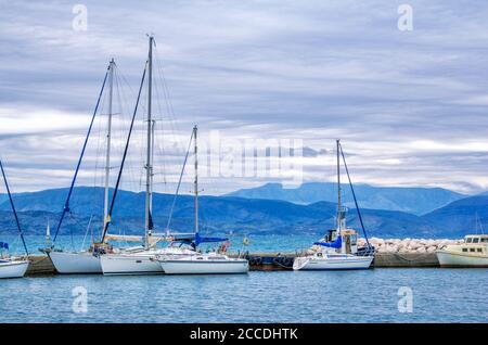 Île de Corfou/Grèce- 4 mai 2019 : vue sur le magnifique port de Kerkyra – mer calme, yachts blancs et ciel bleu avec nuages et montagnes à l'horizon. Banque D'Images