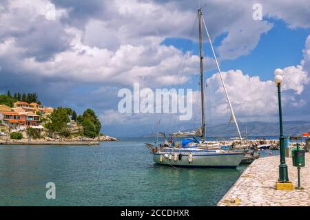 Île de Corfou/Grèce- 6 mai 2019: Vue sur le magnifique village de Kassiopi - lagune de mer avec eau turquoise calme, bateaux et yachts, maisons colorées Banque D'Images