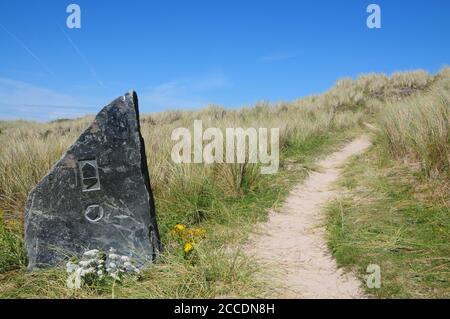 Marqueur de direction de roche sculptée pour le chemin de la côte sud-ouest lorsqu'il traverse le duneland près de Hayle dans le nord de Cornwall. Banque D'Images