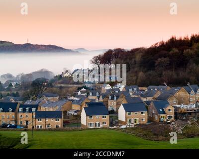 Nouvelles maisons à la périphérie de Buxton dans le Derbyshire Peak District avec brume sur les collines en arrière-plan. Banque D'Images