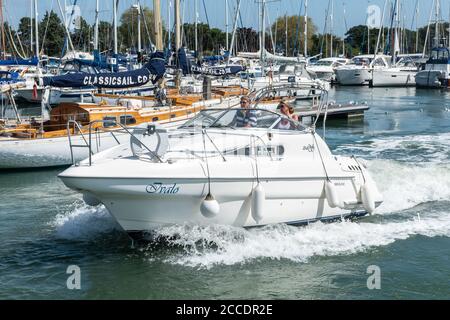 Yachts et bateaux à Chichester Marina, Chichester Harbour, West Sussex, Royaume-Uni - un couple sur un bateau à moteur quittant la marina Banque D'Images