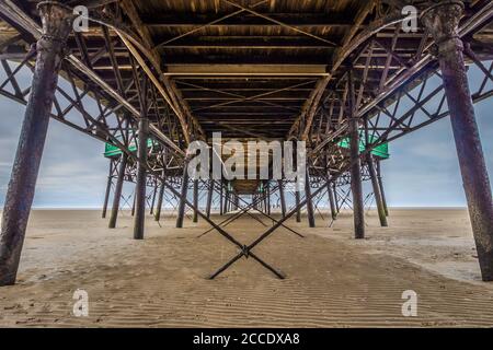 Sous la jetée de Lytham St Annes sur la côte du lancashire. Symétrie dans les anciens piliers et câbles métalliques. Banque D'Images