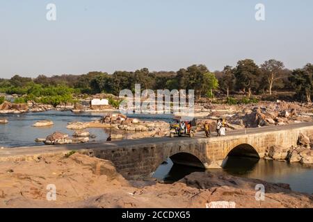 Orcha, Madhya Pradesh, Inde - Mars 2019: Personnes marchant et rickshaws voyageant sur l'ancien pont en pierre au-dessus de la rivière Betwa sur le Tikarmgarh - JH Banque D'Images