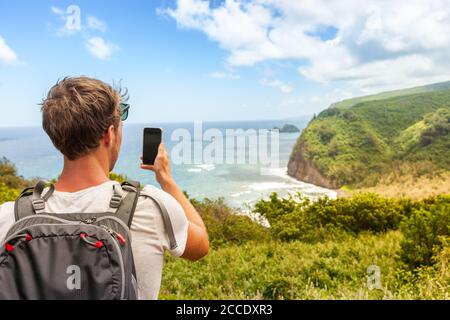 Voyage touriste homme à Hawaï plage États-Unis vacances prendre des photos avec appareil de téléphone mobile de l'océan paysage montagnes arrière-plan. Big Island, Hawaï. Banque D'Images