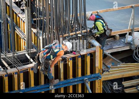 Austin, TX USA 25 juillet 2020: Les ouvriers de la construction portant des équipements de sécurité et des revêtements de visage préparent le coffrage pour la colonne de béton sur le garage de stationnement de la tour de haute élévation qui monte dans le quartier de Rainey Street près du centre-ville d'Austin. Banque D'Images