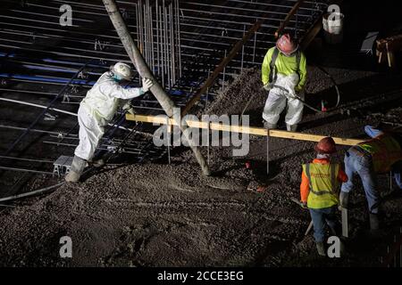 Austin, TX USA 25 juillet 2020: Le béton pompé coule à travers un tube sur le plancher d'un garage de stationnement, partie d'un bâtiment de 53 étages en construction, pendant une nuit-verse près du centre-ville d'Austin,. Banque D'Images