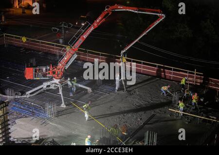 Austin, TX USA 25 juillet 2020: Le béton pompé coule à travers un tube sur le plancher d'un garage de stationnement, partie d'un bâtiment de 53 étages en construction, pendant une nuit-verse près du centre-ville d'Austin,. Banque D'Images