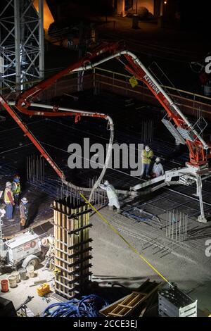 Austin, TX USA 25 juillet 2020: Le béton pompé coule à travers un tube sur le plancher d'un garage de stationnement, partie d'un bâtiment de 53 étages en construction, pendant une nuit-verse près du centre-ville d'Austin,. Banque D'Images