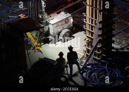 Austin, TX USA 25 juillet 2020 : un projecteur alimenté par un générateur éclaire les équipes de béton travaillant sur le garage d'un bâtiment de 53 étages pendant une nuit dans le centre-ville d'Austin, TX. D'énormes projets de construction se poursuivent sans relâche au Texas malgré la pandémie de COVID-19 à l'échelle nationale et l'État frappé par plus d'un demi-million de cas et plus de 10,000 000 décès. Banque D'Images