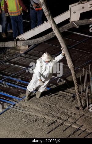 Austin, TX USA 25 juillet 2020: Le béton pompé coule à travers un tube sur le plancher d'un garage de stationnement, partie d'un bâtiment de 53 étages en construction, pendant une nuit-verse près du centre-ville d'Austin,. Banque D'Images