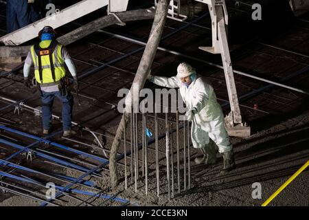 Austin, TX USA 25 juillet 2020: Le béton pompé coule à travers un tube sur le plancher d'un garage de stationnement, partie d'un bâtiment de 53 étages en construction, pendant une nuit-verse près du centre-ville d'Austin,. Banque D'Images