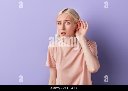 grave femme malheureuse à l'écoute des offres spéciales de vente.femme essayant d'écouter des potins. portrait de gros plan, boutique de studio Banque D'Images