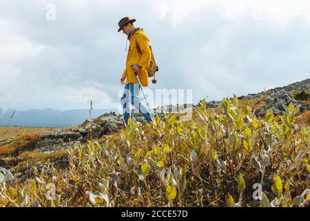 beau homme avec un sac à dos marche seul sur une montagne, solitude, pleine longueur vue latérale photo, copier l'espace Banque D'Images