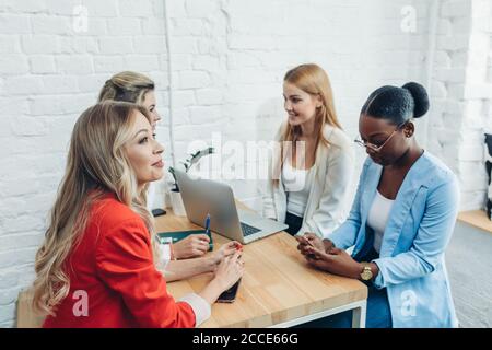 Les femmes le travail d'équipe et team building concept. Démarrage positif partenaires féminines dans les tenues de discuter des idées de nouvelle stratégie de développement à Banque D'Images