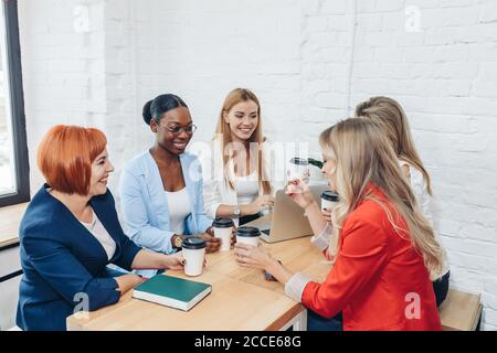 Les femmes le travail d'équipe et team building concept. Démarrage positif partenaires féminines dans les tenues de discuter des idées de nouvelle stratégie de développement à Banque D'Images