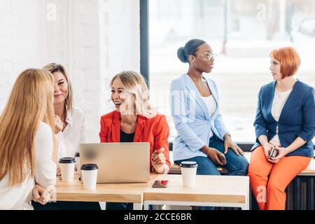 Groupe de femmes les blogueurs sont qualifiés pour la rédaction de la page web de support de la saisie sur clavier d'ordinateur, assis à table dans Office. Banque D'Images