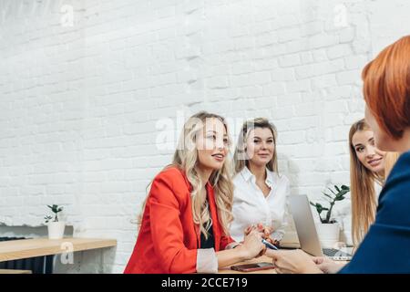 Jolie rousse enseignante s'adressant à un groupe de jeunes étudiantes à séminaire de formation, toutes les femmes en tenue casual vestes colorées. Banque D'Images