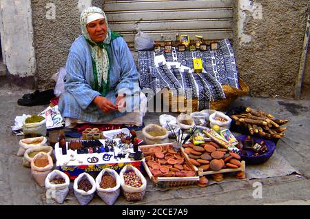 Octobre 2005 - la Médina est une zone entourée de murs qui contient un labyrinthe de souks (marchés), ruelles, magasins et artisans vendant leurs produits . Acheter implique toujours de marchander. Cette photo montre une femme assise au sol qui vend ses produits (épices, bâtonnets d'encens, noix, parfums, punaises, etc.) Banque D'Images