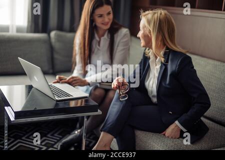 Concept de petite entreprise. Jeunes partenaires créatifs de petites entreprises travaillant avec un nouveau projet de démarrage dans un bureau moderne. Deux jeunes femmes assises sur un canapé et Banque D'Images