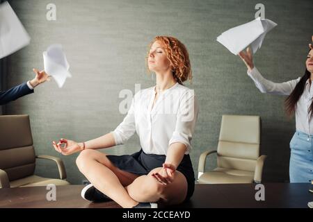 Concept de détente. Sereine femme d'affaires méditant dans le bureau mettant de côté, postpone toutes les questions urgentes. Une femme qui gérait l'esprit s'en moque Banque D'Images
