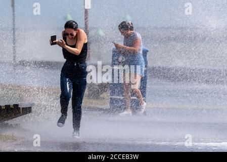 Deux jeunes femmes blanches qui traversent des vagues écrasant à Southend on Sea, dans l'Essex, au Royaume-Uni, pendant les vents violents de Storm Ellen, qui s'mouille, s'enivrant Banque D'Images