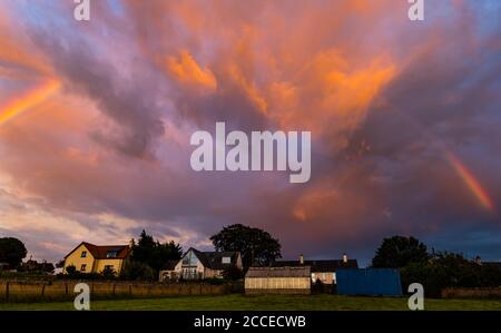 East Lothian, Écosse, Royaume-Uni, 21 août 2020. Météo au Royaume-Uni : la tempête Ellen frappe l'est du pays, mais une courte pause dans les nuages au coucher du soleil crée un ciel nocturne spectaculaire avec un arc-en-ciel au-dessus des maisons rurales Banque D'Images