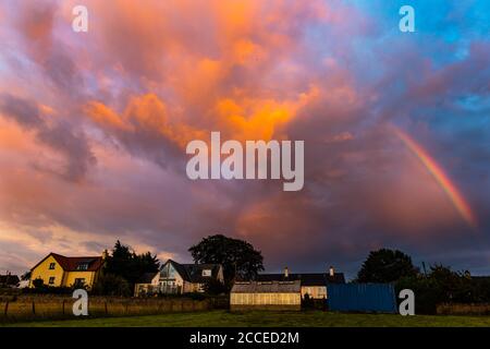 East Lothian, Écosse, Royaume-Uni, 21 août 2020. Météo au Royaume-Uni : la tempête Ellen frappe l'est du pays, mais une courte pause dans les nuages au coucher du soleil crée un ciel nocturne spectaculaire avec un arc-en-ciel au-dessus des maisons rurales Banque D'Images