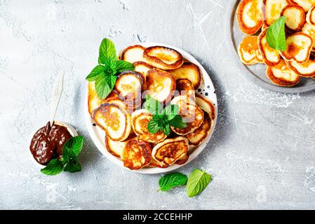 Mini crêpes sur plaque, vue de dessus de la table scène sur un fond gris. Banque D'Images