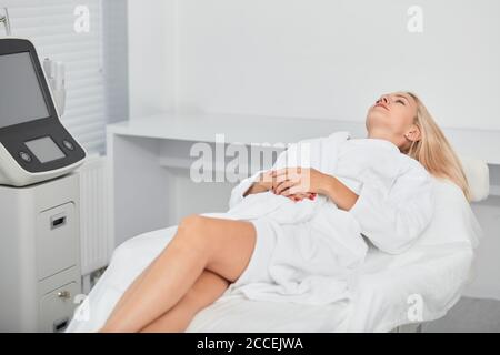 Belle et décontractée jeune femme en peignoir couché et en attente soin du visage, photo de gros plan. Détente, style de vie Banque D'Images