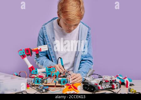 Un jeune homme du caucase tenant des cris plus secs, passant du temps libre après l'école dans le club d'ingénierie, jouant à assembler des robots. Un garçon malin enfant Banque D'Images