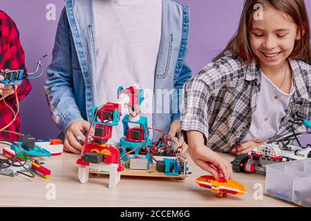 portrait d'enfants souriants positifs jouant avec la robotique isolée sur fond violet, futurs ingénieurs. technologies d'innovation Banque D'Images