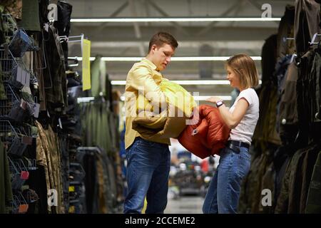 couple essayer d'emballer sac de couchage pour le camping en magasin, les voyageurs veulent acheter de l'équipement sportif et d'autres choses pour le camping Banque D'Images