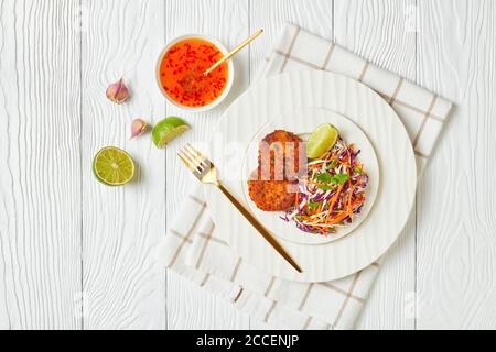 gâteaux de poisson thaïlandais frits servis avec salade de coleslaw sur une assiette sur une table en bois avec sauce au piment doux, vue horizontale d'en haut, plat Banque D'Images