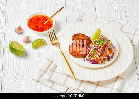 beignets de poisson thaïlandais frits servis avec salade de coleslaw sur une assiette sur une table en bois avec sauce au piment doux, vue sur le paysage depuis le dessus, gros plan Banque D'Images