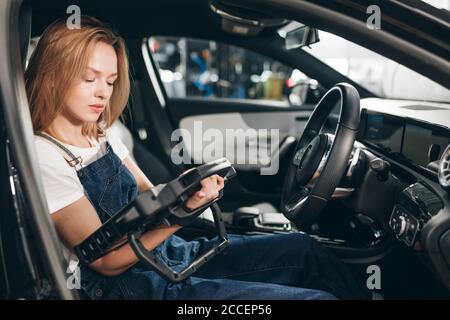 mécanicien femme avec scanner de diagnostic automobile assis dans la voiture. travail, profession. gros plan Banque D'Images