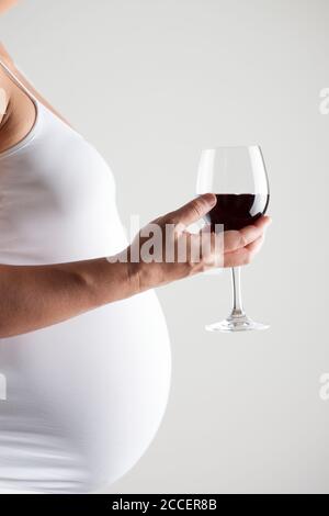 Femme enceinte tenant un verre de vin rouge Banque D'Images