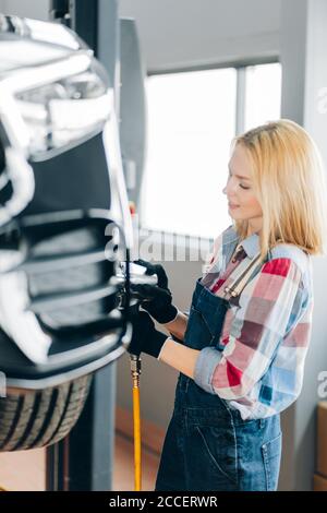 magnifique fille concentrée sur le dévissage de la roue. gros plan vue latérale photo. Banque D'Images