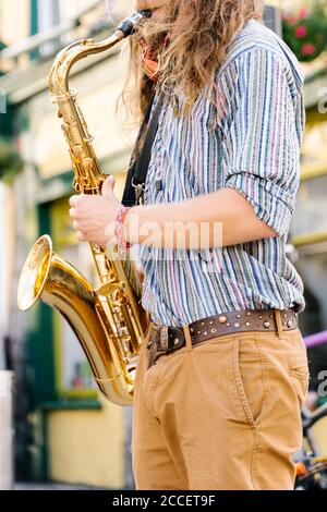 Photo verticale des mains d'un jeune homme avec Saxophone à cheveux longs dans la rue de Galway Banque D'Images