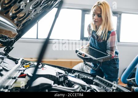 jeune femme vérifiant la consommation de carburant, le calage de la voiture et les caractéristiques de performance.gros plan photo Banque D'Images