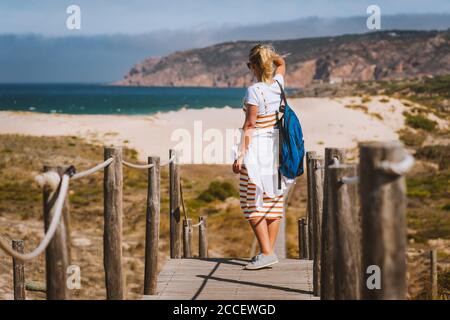 Touriste féminin adulte bénéficiant d'une vue sur la plage de Praia do Guincho. Cascais, Portugal. C'est la plage de l'Atlantique drapeau bleu populaire pour le surf, le windsurf Banque D'Images