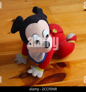 Mickey Mouse Un Jouet A Piles Pour Bebe Officiel De Disney Un Bavoir Et Un Bebe Rouge Poussent Sur Un Bois Sol Photo Stock Alamy