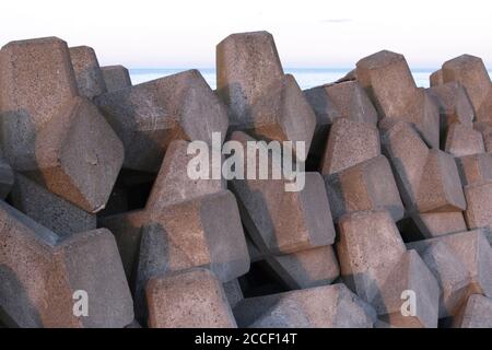 Gros plan des tétrapodes en béton utilisés pour prévenir l'érosion côtière d'une réserve naturelle de rivage sablonneux et de marais à Hokkaido, au Japon Banque D'Images