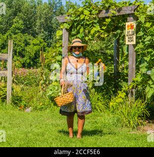 un signe d'espoir : une jeune femme qui traverse l'arbre du jardin avec des herbes et des fleurs récoltées de la ferme communautaire Banque D'Images