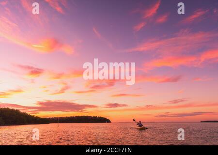 Kayakiste kayak de mer kayak au coucher du soleil sur l'été océan nature paysage. Paysage incroyable avec ciel rose Banque D'Images