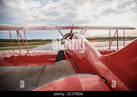 Avion d'époque rouge brillant restauré sur l'aérodrome au lever du soleil Maine Banque D'Images
