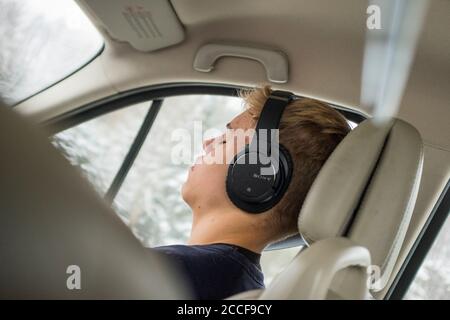 Garçon (16 ans) avec casque dans une voiture Banque D'Images