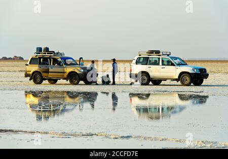 Deux véhicules à quatre roues motrices avec personnel de garde se trouvent devant une saumure au bord du lac de sel d'Assale, Hamedala, vallée de Danakil, Afar Regio Banque D'Images